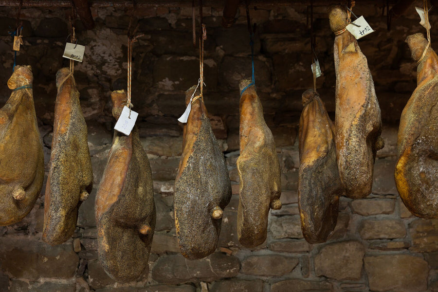 Prosciutti appesi a stagionare nella cantina in pietra